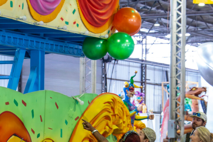 A woman giving a tour of a green Mardi Gras float to a group of children.