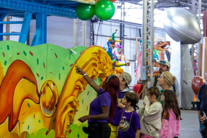 A Mardi Gras World tour guide points out features of a float to a group of children.